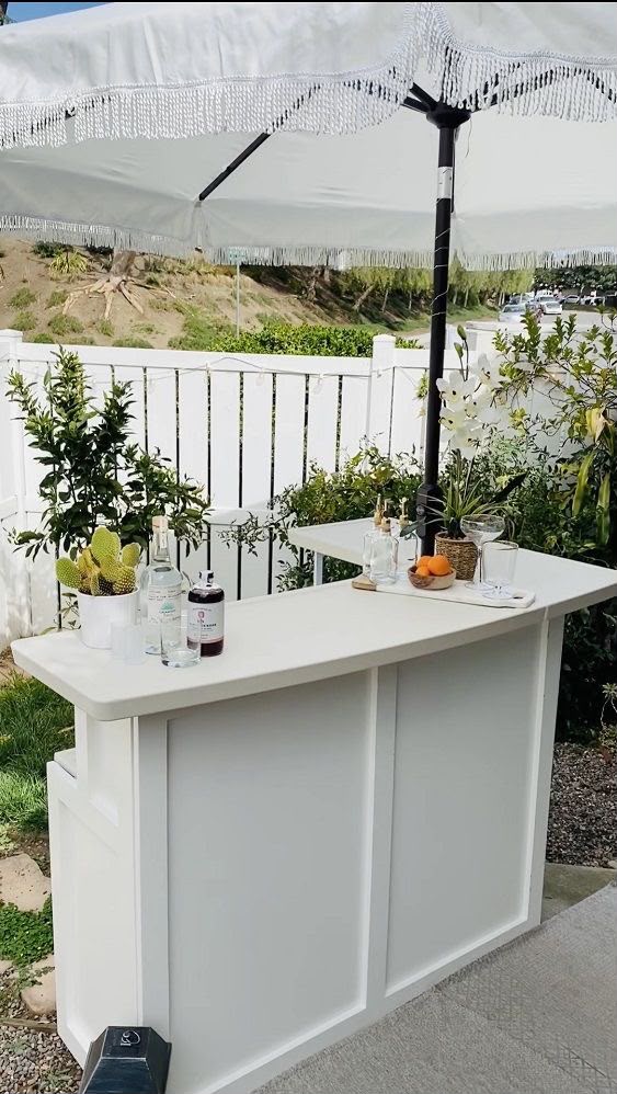 White mobile bar with gin and coupes on a patio